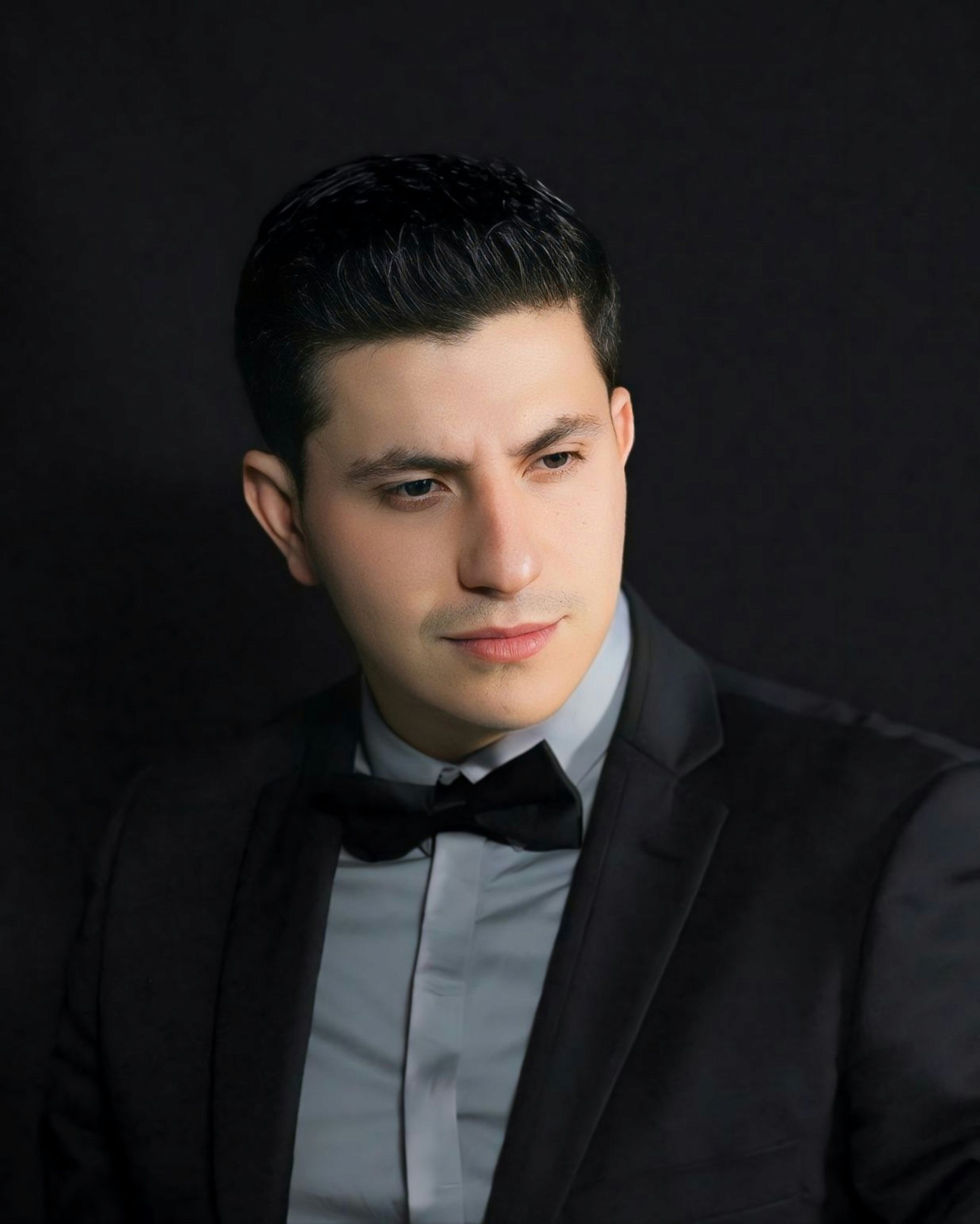 a man in a tuxedo poses for a picture