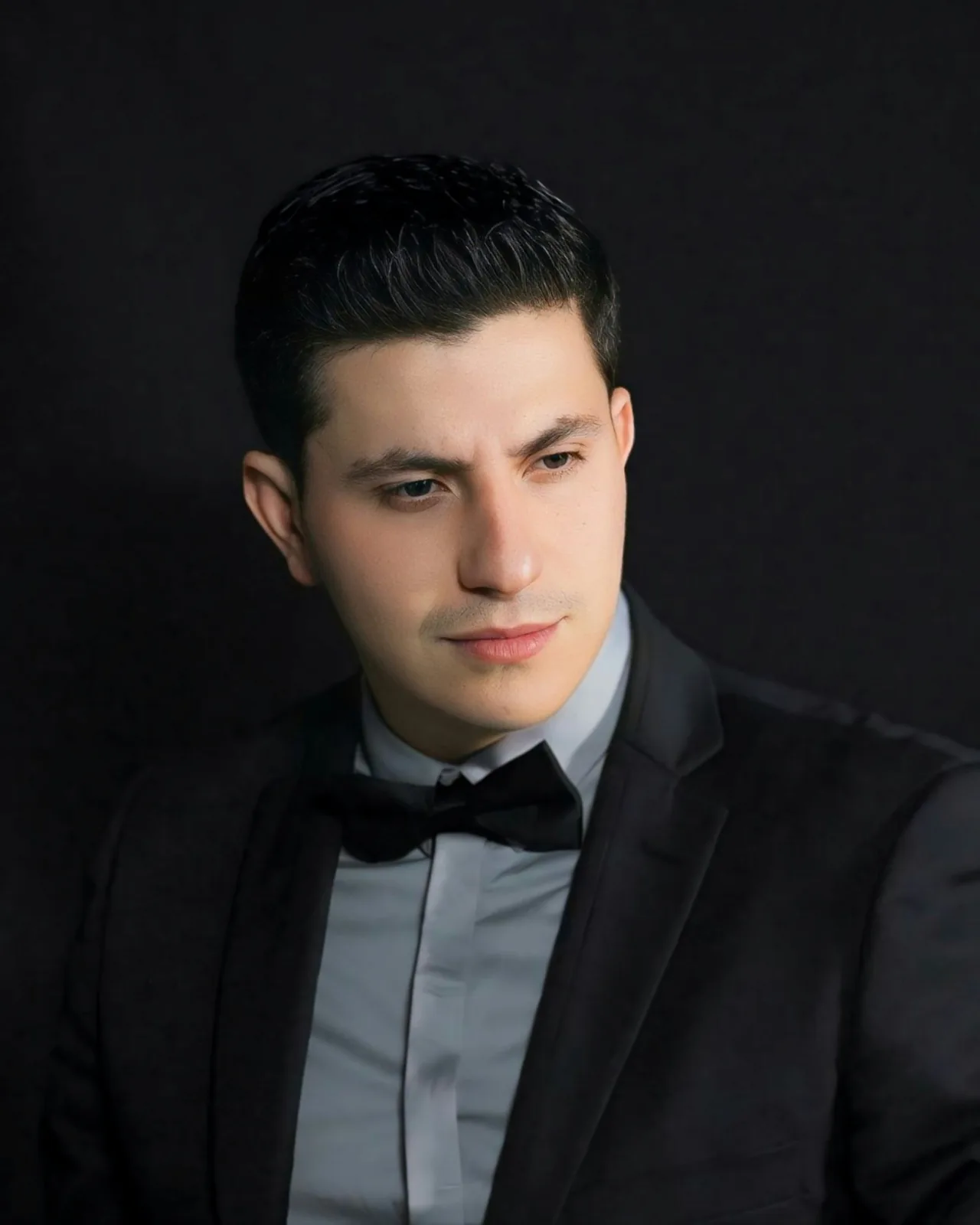 a man in a tuxedo poses for a picture
